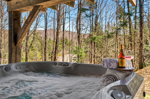 Forest-view hot tub on covered deck—private soak with mountain vistas.