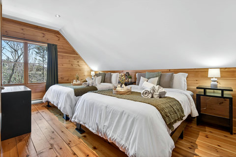 Cozy loft bedroom with twin beds, forest view, and cabin warmth