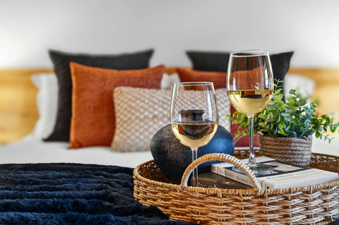 Cozy bedroom retreat with wine, books, and plush, stylish touches
