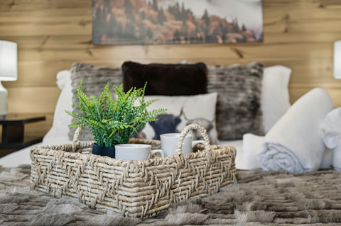 Cozy, cabin‑chic bedroom with plush linens and a welcome tray