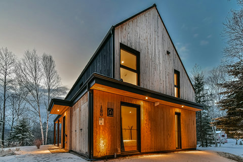 Modern wood-clad chalet glowing warmly in a serene snowy setting