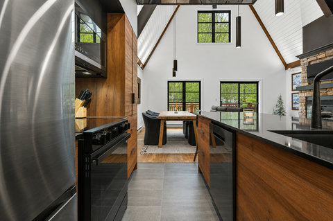 Modern vaulted kitchen with wood finishes, natural light, and open dining space