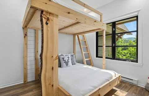 Rustic bunk room with loft bed, natural light, and cozy cabin charm