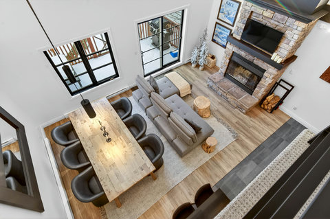 Spacious great room with stone fireplace, TV, and large dining table