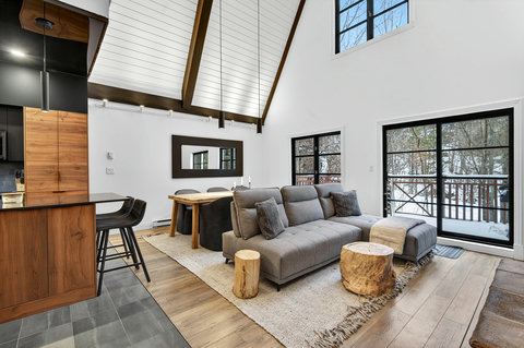 Bright vaulted great room with wooded views, cozy seating, and modern rustic style