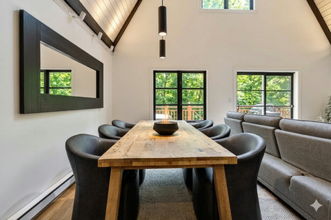 Bright vaulted dining area with rustic table, modern seating, and leafy views