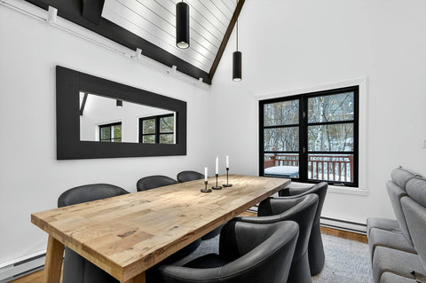 Modern vaulted dining room with wood table and snowy window views