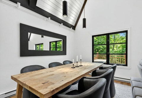 Bright vaulted dining room with rustic table and serene tree views