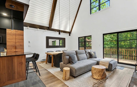 Bright vaulted living space with deck access and peaceful forest views