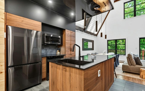 Modern open-concept kitchen with island seating and stunning wooded views