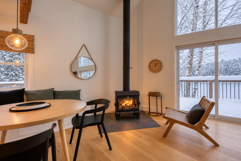 Cozy wood stove, soaring windows, and serene snowy forest views