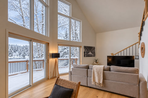 Sunlit great room with soaring windows and peaceful snowy deck views