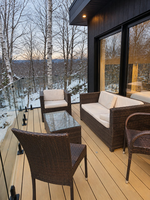 Private forest-view balcony with cozy seating and serene snowy scenery