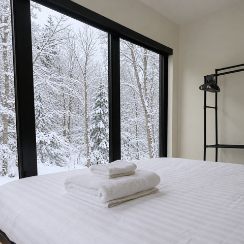 Wake up to serene snowy forest views from this cozy modern bedroom