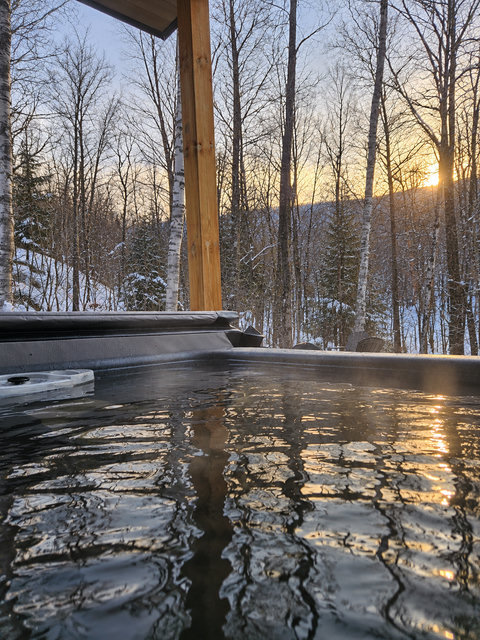 Private hot tub with snowy forest views at sunset