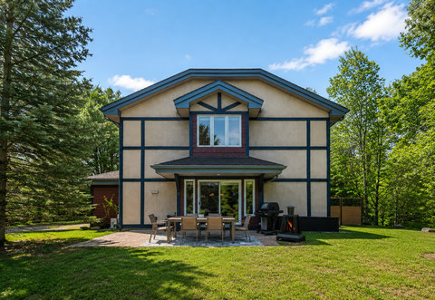 Private backyard patio with outdoor dining, grill, and wooded views