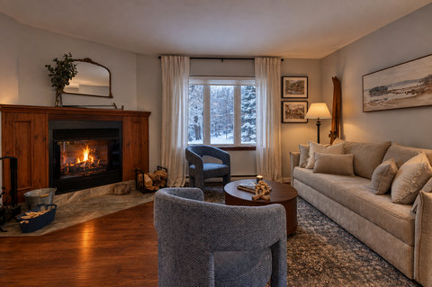 Cozy fireside living room with snowy forest views and plush seating