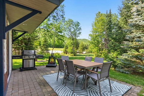 Private forest-view patio with outdoor dining, grill, and fire feature