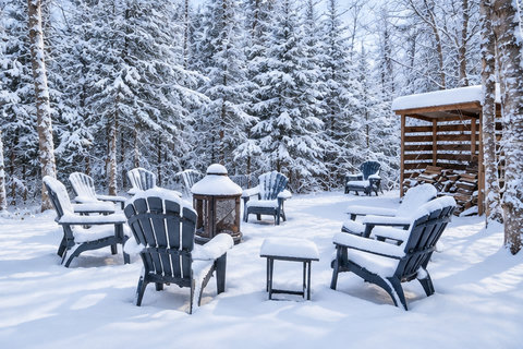 Snowy forest fire pit with Adirondack chairs for a cozy winter retreat