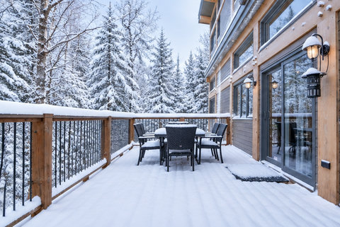 Snowy private deck with forest views and outdoor dining seating