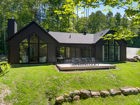 Modern forest retreat with soaring windows, deck seating, and a private yard