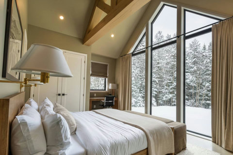 Vaulted bedroom with panoramic windows and stunning snowy forest views