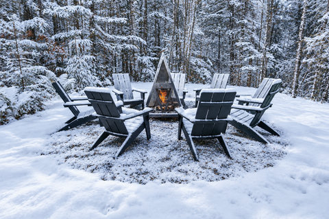 Snowy forest fire pit with Adirondack seating for cozy winter nights