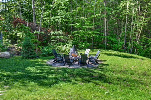 Private wooded fire pit area with Adirondack chairs and serene lawn