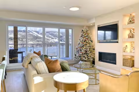 Modern lakeview lounge with fireplace, balcony, and stunning mountain scenery