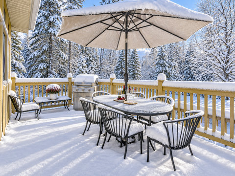 Snowy private deck with forest views, dining area, and BBQ grill