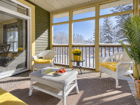 Sunny screened porch with cozy wicker seating and serene snowy views