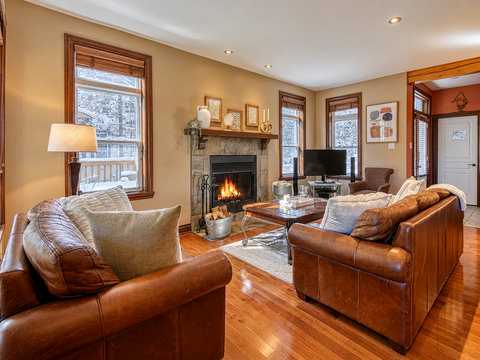 Cozy leather lounge with stone fireplace and snowy mountain views