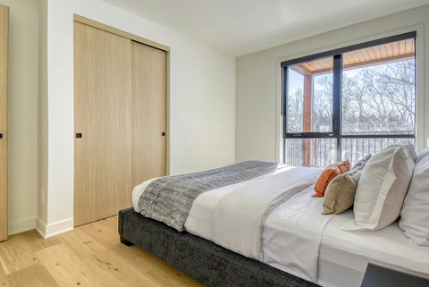 Bright modern bedroom with balcony access and serene treetop views