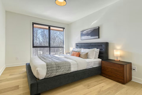 Bright modern bedroom with plush bed and serene tree-view window