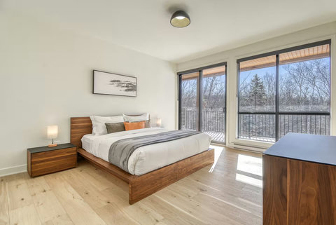Bright modern bedroom with private balcony and serene treetop views
