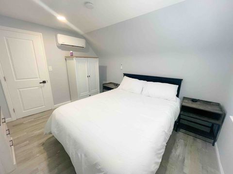 Queen size bed, independent split air conditioning cooling and heating unit, night stand on each side of the bed with USB charging ports and outlets, large wardrobe closet, and a dresser. 