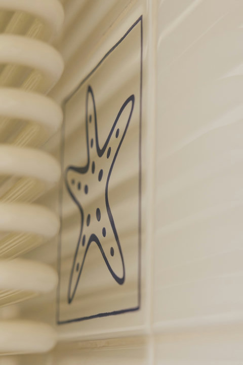 Charming original details throughout — like this hand-painted starfish tile by the heated towel rail