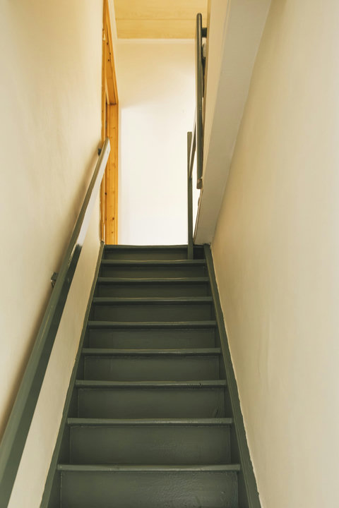 Characterful green staircase leading up to the bedrooms — authentic Bruges townhouse charm
