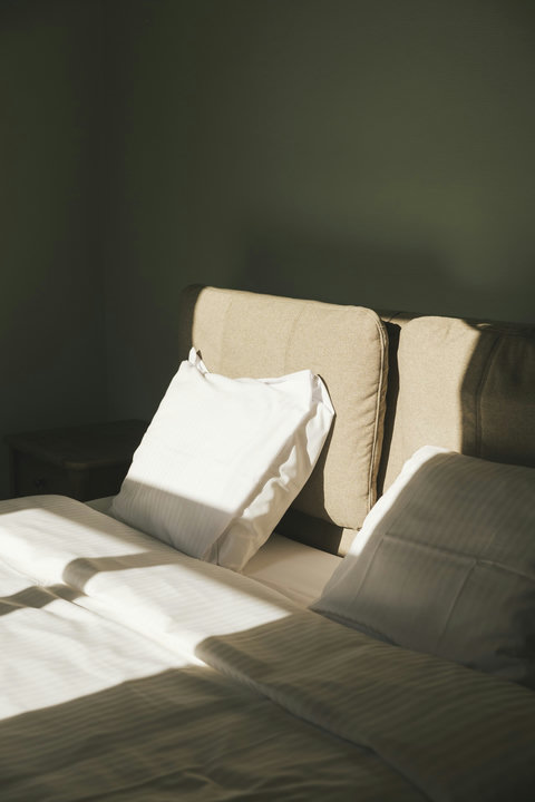 Soft morning light on the double bed — calming sage-green tones for a restful night