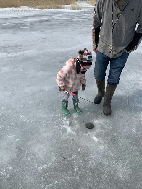 Kids  learning to catch fish through the ice