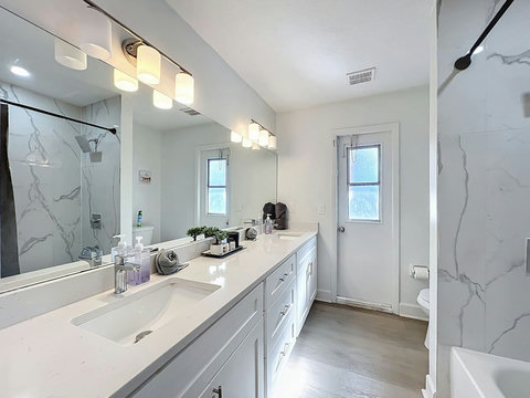 Full bathroom with two sinks  a hut tub toilet and direct access to the pool and backyard.