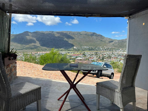 Mountain-view outdoor patio with a private dining table and chairs, overlooking Fish Hoek and the surrounding mountains.