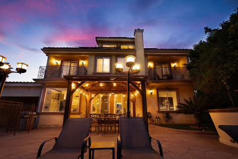 Private backyard with pool, lounge chairs, and a beautifully lit patio perfect for evening relaxation.