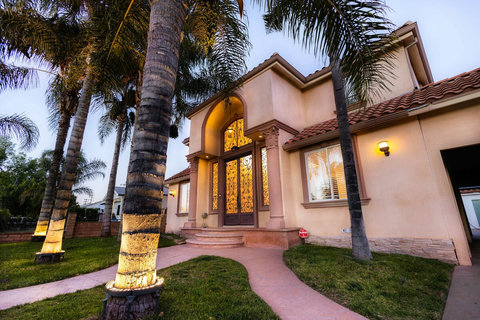 Elegant front entrance with palm trees and a grand double door entry.