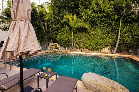Private pool surrounded by lush greenery with lounge chairs and shaded seating for relaxing poolside.