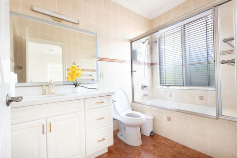 Bright full bathroom featuring a vanity with storage, large mirror, and a shower tub combination with glass sliding doors.