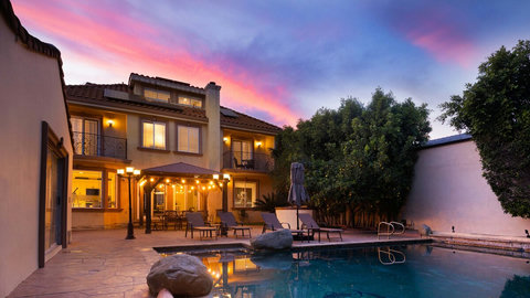 Covered outdoor patio with string lighting and seating area overlooking the pool, ideal for gatherings or quiet nights outside.