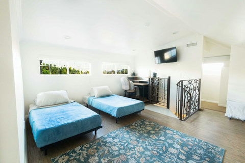 Spacious upper level guest room featuring two beds, open floor space, a cozy tucked away area under the sloped ceiling, plus a fully equipped workspace with high speed internet up to 1 Gig/s, ethernet, keyboard, and mouse.