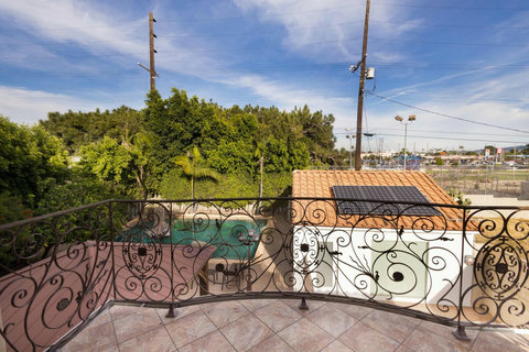 Balcony connected to the Junior Suite featuring decorative iron railings and an open view of the backyard, pool area, and surrounding greenery.