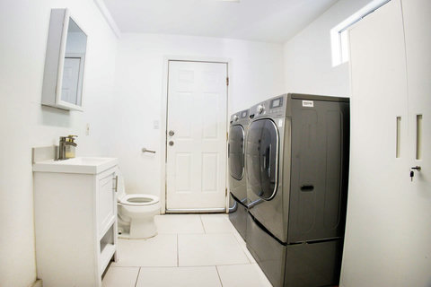 Utility space featuring washer and dryer along with a half bathroom, located near the pool area for added convenience.